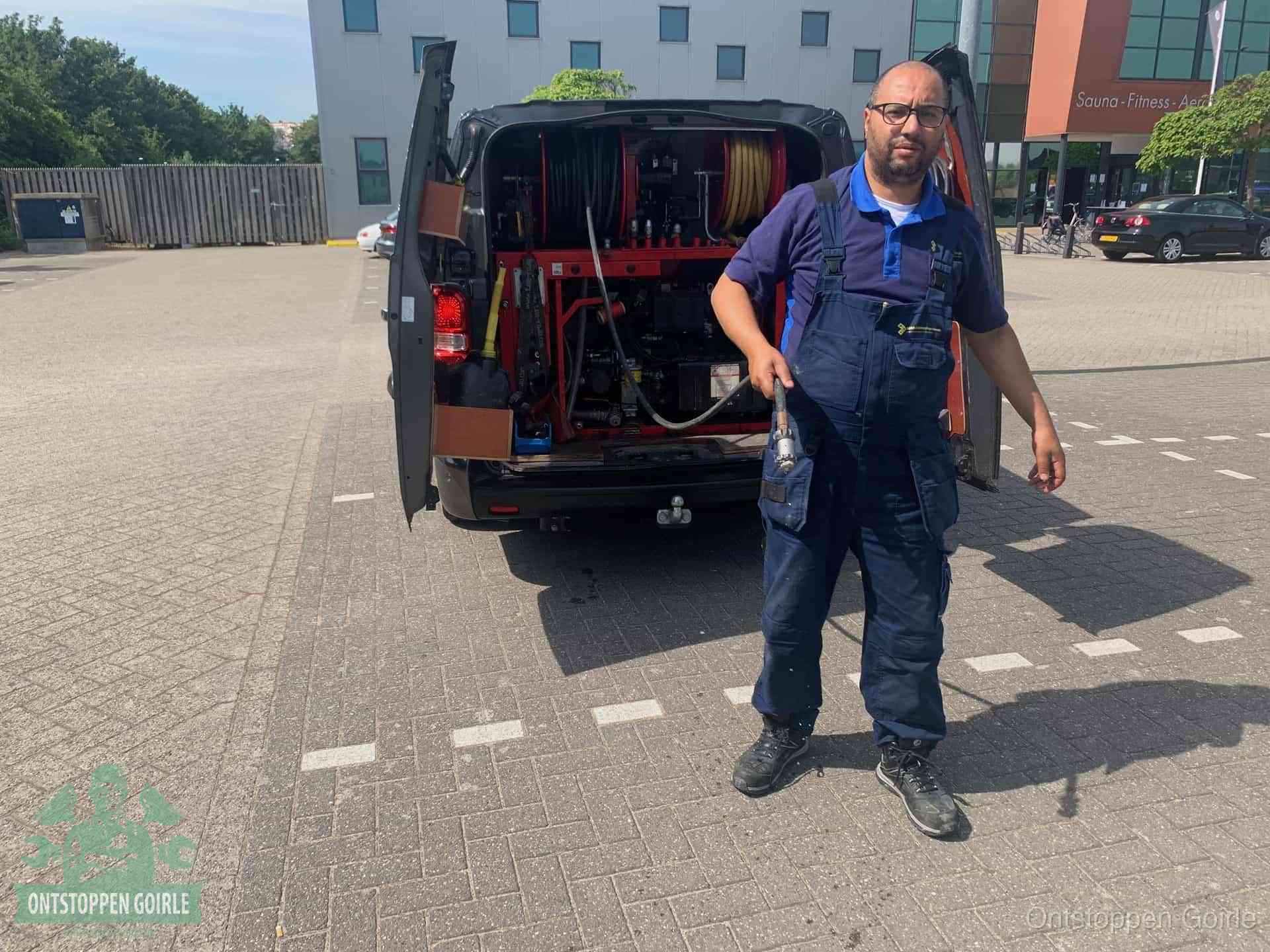 Een monteur bij zijn bestelbus met een hogedruk- en rioolreinigingsunit, klaar om de oorzaak van terugkerende wc-verstoppingen aan te pakken in Goirle