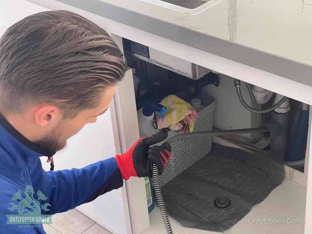 Een monteur voert een flexibele ontstoppingsveer in de afvoer om een verstopping voorbij de bocht van het toilet te bereiken in Goirle
