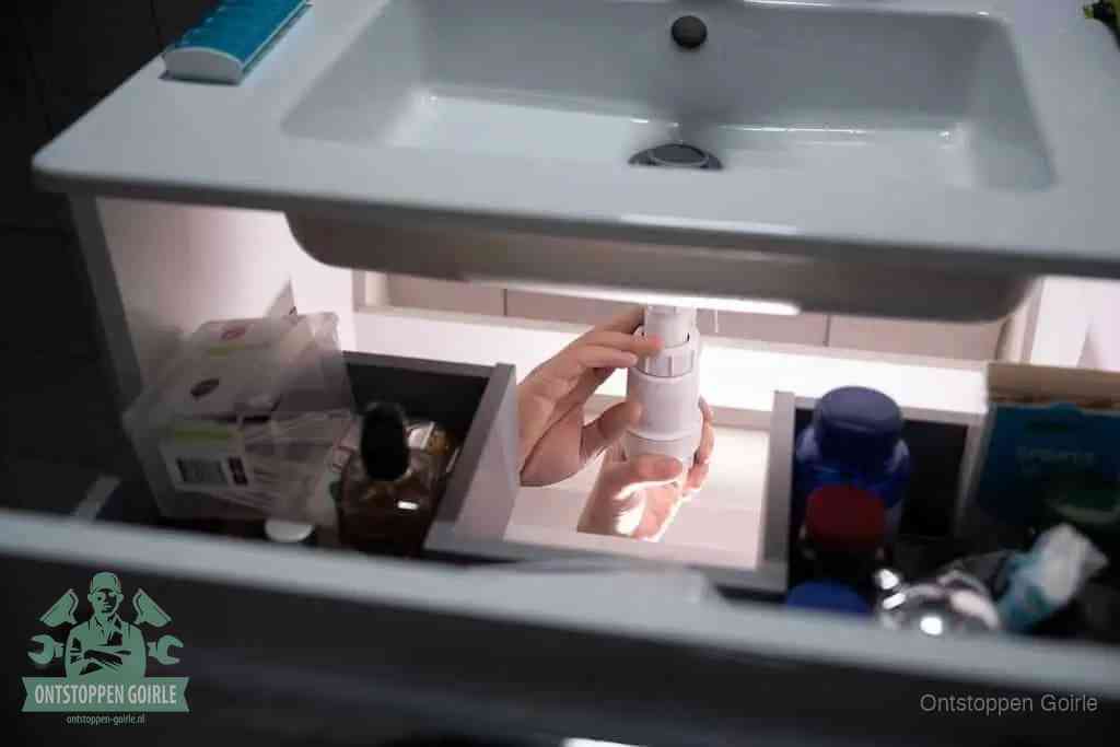Een pompfles met zeep boven een wastafel in de toiletruimte, de warm water en afwasmiddel-methode om de wc te ontstoppen in Goirle