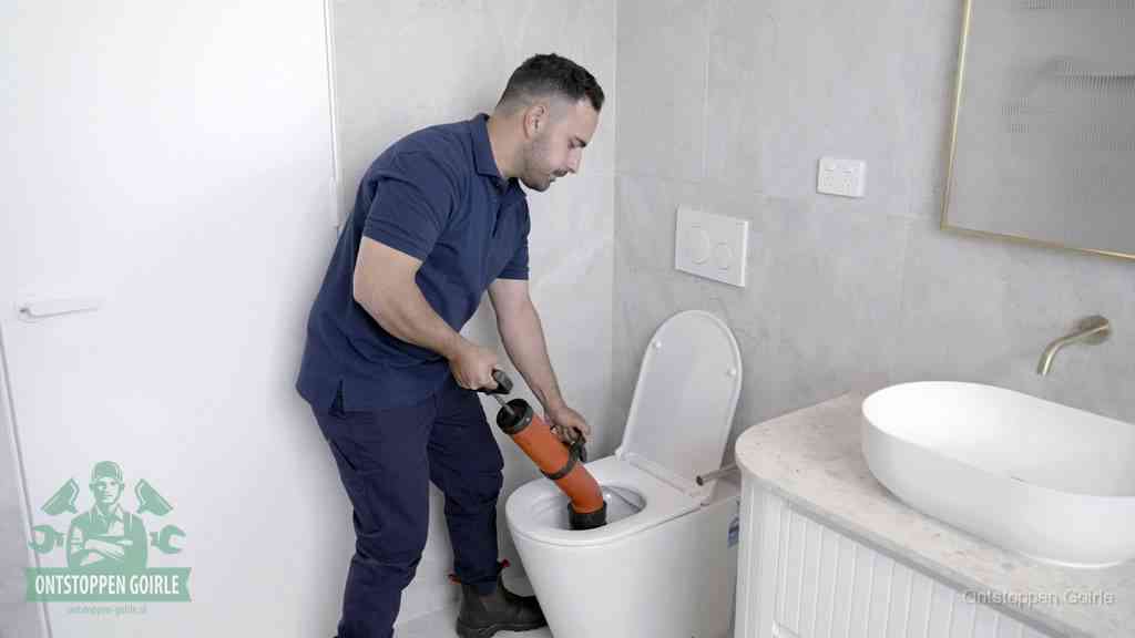 Een monteur gebruikt een handmatige perspomp (toiletontstopper) op een wandcloset tijdens het professioneel wc ontstoppen in Goirle