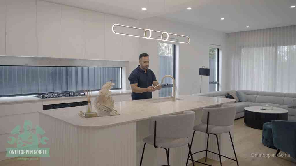 Een bewoner bij de keukenspoelbak die zelf aan de slag gaat met een verstopte gootsteen in Goirle